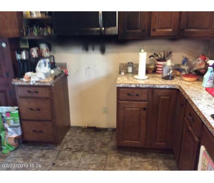 Kitchen with smoke damaged walls and cluttered cabinet tops