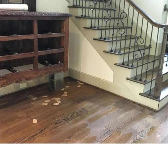  hardwood floorboards wet from flooding, furniture on blocks, stairway close by