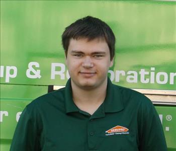 Male SERVPRO employee standing in front of a SERVPRO vehicle. 