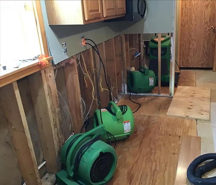 SERVPRO air movers and a dehumidifier operating in a room with flood cuts and removed flooring