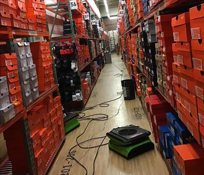 SERVPRO stackable air movers and moisture collection for dehumidifiers between two stocked warehouse shelves