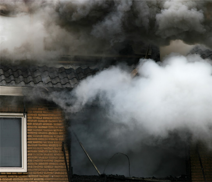 smoke billowing from the windows of a home